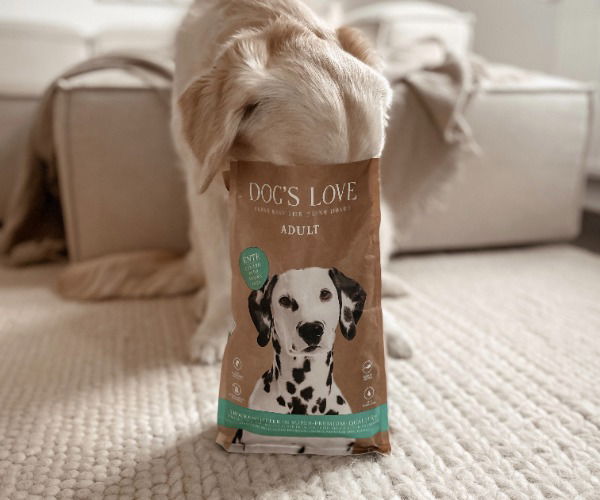 Hund steckt seinen Kopf in eine Packung Trockenfutter von Dog's Love