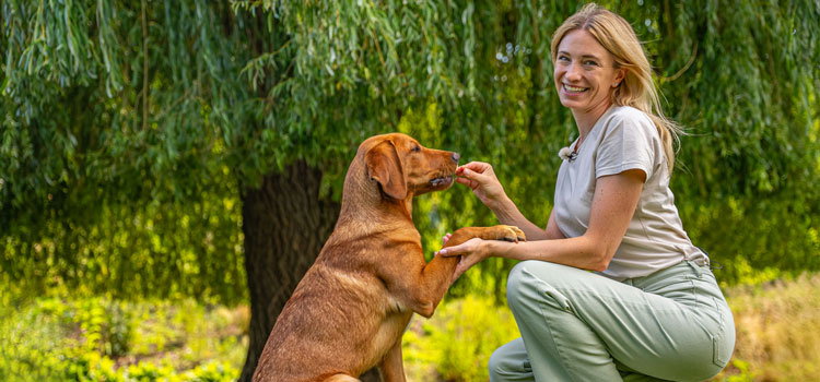 Katharina Miklauz mit ihren Hunden Fynn, wie sie ihm einen Snack gibt