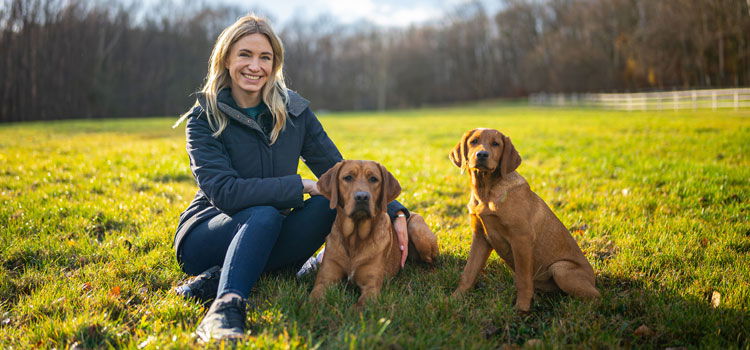 Katharina Miklauz mit ihren Hunden Fynn und Daisy auf einer Wiese