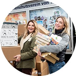 Frauke Ludiwig y Katharina Miklauz sosteniendo y donando productos de DOG'S LOVE.
